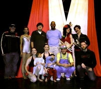 Group of Circus Performers posing in front of red and white fabric. 